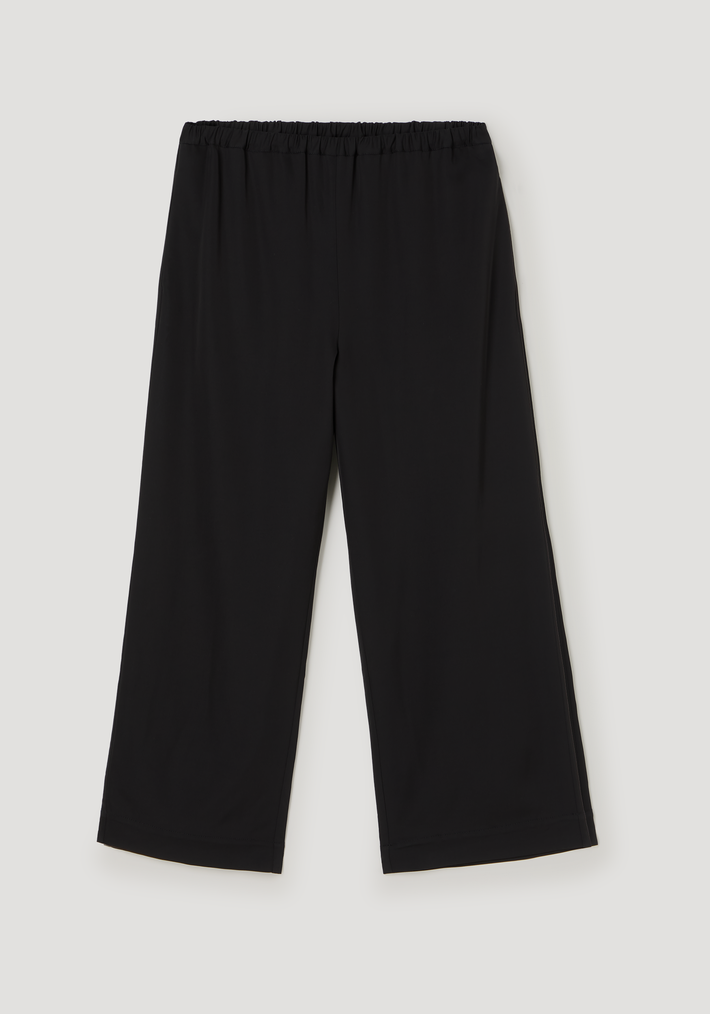 Cropped wide leg trousers in technical jersey, featuring an ankle-length loose leg, elastic waistband, and side seam pockets, laid flat on a light surface.