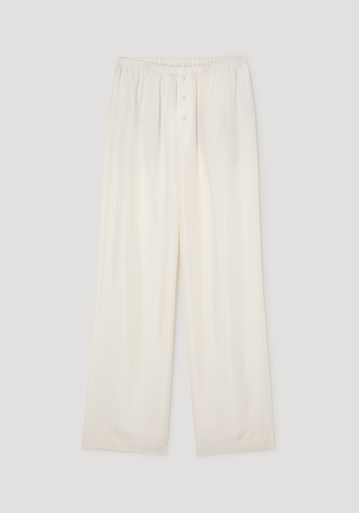 Silk pyjama trousers in a loose-leg style with an elastic waistband and three-button front, laid flat to show lightweight, silky fabric.