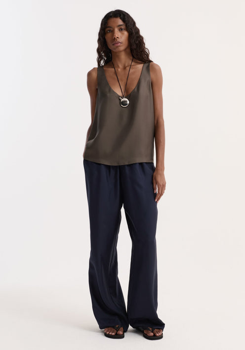 Model wearing Silk pyjama trousers | night; features wide-leg, elasticated waistband. Styled with a sleeveless top, necklace, and sandals for a minimalist look.