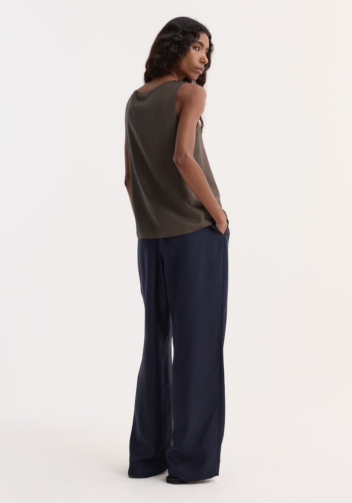 Model in Silk Pyjama Trousers | Night, featuring wide-leg, elastic waistband, faux fly with button detail. Styled with a sleeveless top and black shoes.