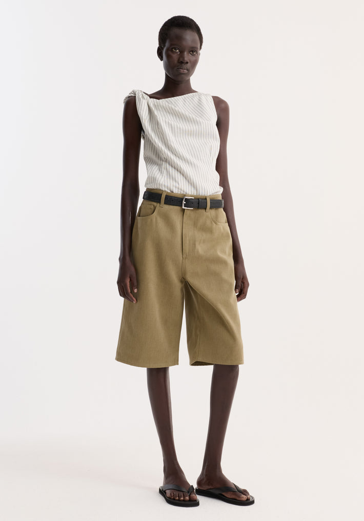 Model wearing Baggy fit denim shorts in sage, featuring a relaxed, knee-length design with a black leather belt, paired with a pin-striped one-shoulder top.