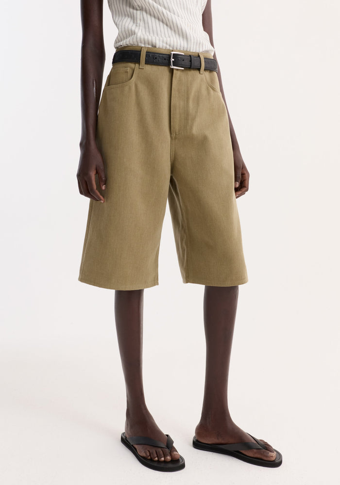 Baggy fit denim shorts in sage, featuring a loose knee-length style, paired with a black belt and sleeveless rib-knit top.