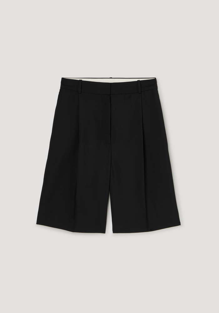 Tailored single pleat shorts in black, featuring a fitted waistband, side pockets, and knee-length wide-legged silhouette, crafted from a lightweight wool-mohair blend.