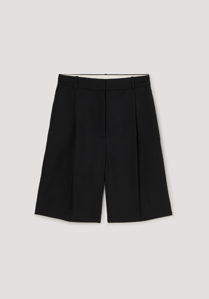 Tailored single pleat shorts in black, featuring a fitted waistband, side pockets, and knee-length wide-legged silhouette, crafted from a lightweight wool-mohair blend.