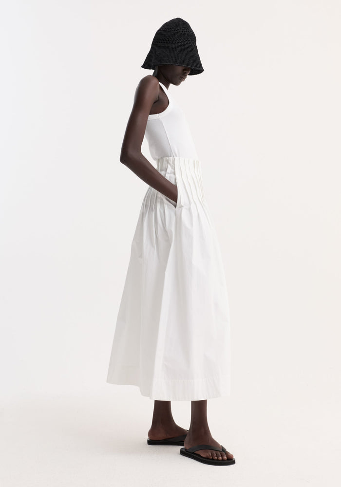 Model in Pleated poplin maxi skirt, optic white, high-waisted with pleated waist and side-seam pockets, paired with a fitted tank and flip-flops.
