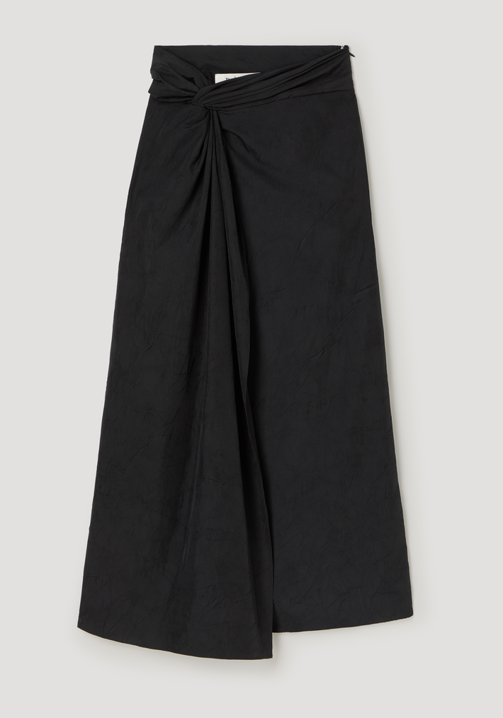 Sarong textured skirt | black with a twisted knot waist, draped front panel, concealed zip, and subtle center slit, laid flat on a neutral backdrop.