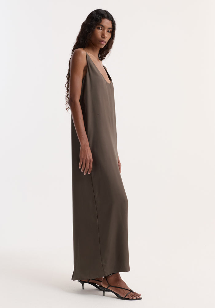 Model wears Silk scoop-neck dress | earth, showcasing a floor-length, sleeveless design with a deep scoop neckline and relaxed silhouette, paired with black low-heeled sandals.