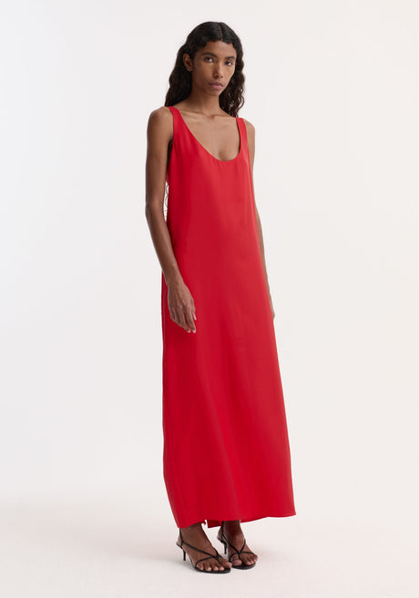 Silk scoop-neck dress in red, sleeveless, floor-length, worn by a model. Features a relaxed silhouette, crafted from pure silk, paired with black strappy sandals.