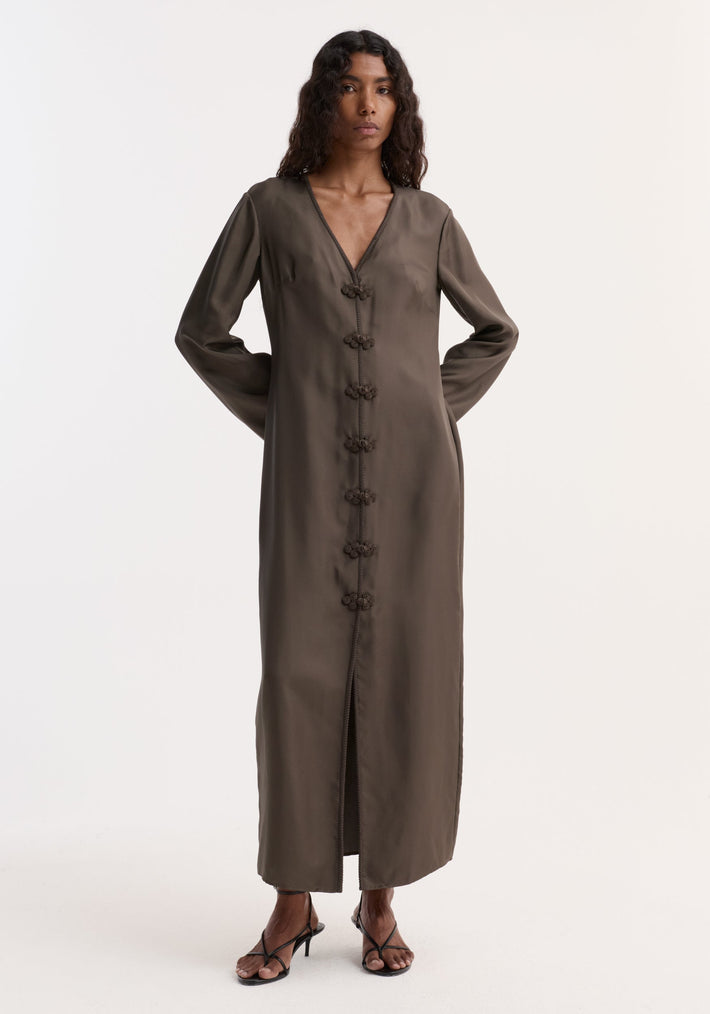 Model in Pankou closure silk dress | earth, showcasing a long, olive-green, V-neck design with decorative closures, long sleeves, and front slit.