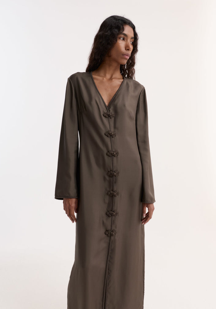 Model in Pankou closure silk dress | earth, showcasing a long, olive-green, V-neck design with decorative closures, long sleeves, and front slit.