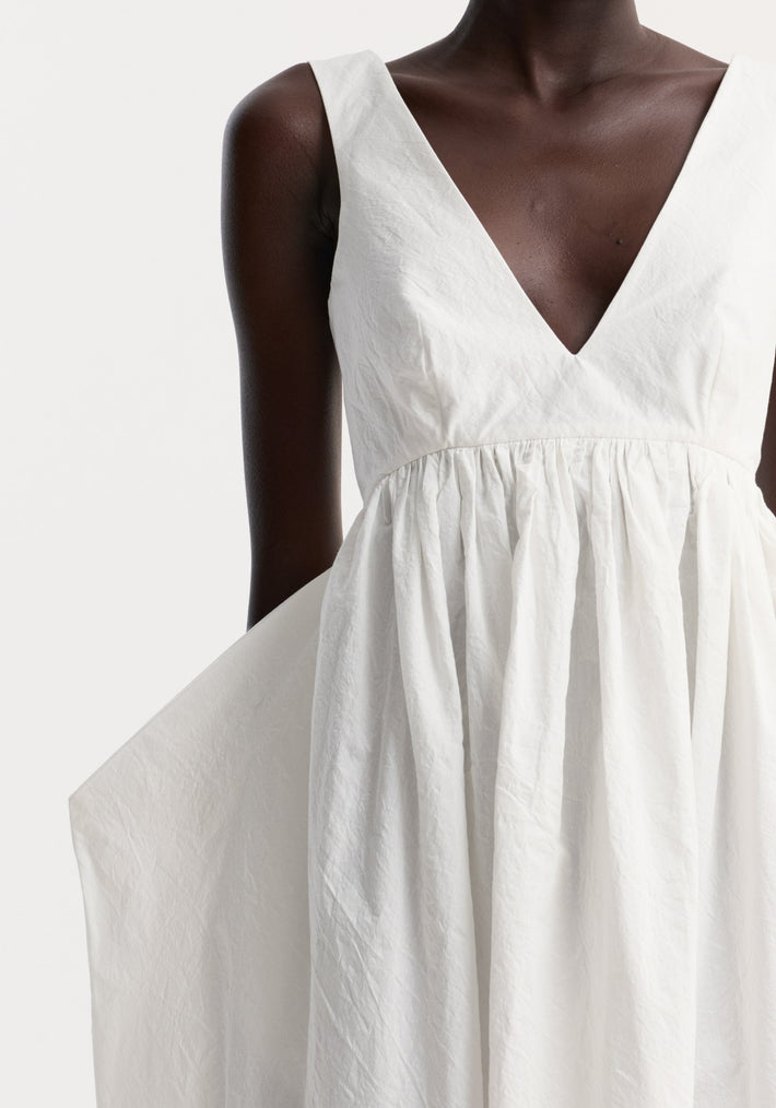 Model wearing a Sculptural textured cotton dress in off white, featuring a sleeveless design with a deep V-neckline and voluminous gathered skirt.