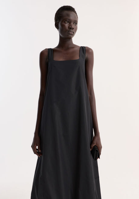 Technical volume dress | black, worn by a tall model, features a sleeveless design, square neckline, and balloon hemline, creating a minimalist and modern silhouette.