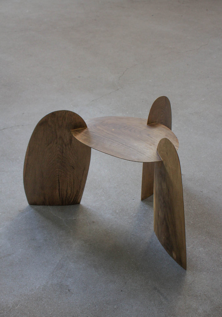 Sculpted Stool | 4673: A low, sculptural stool crafted from interlocking oak panels, forming tripod legs and a round, dished top. Handcrafted by Arne Kristian.