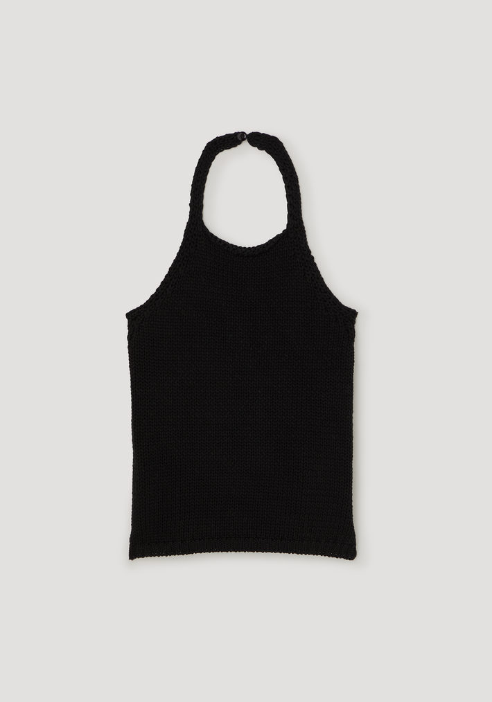 Chunky knit halter top in black, hand-knit style with side slits, button closure at the neck, crafted from 100% cotton, laid flat.