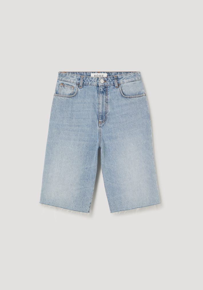 Baggy fit denim shorts in classic blue, Bermuda-length with raw hem, front pockets, belt loops, metal button, 100% cotton, showcasing a relaxed and timeless style.