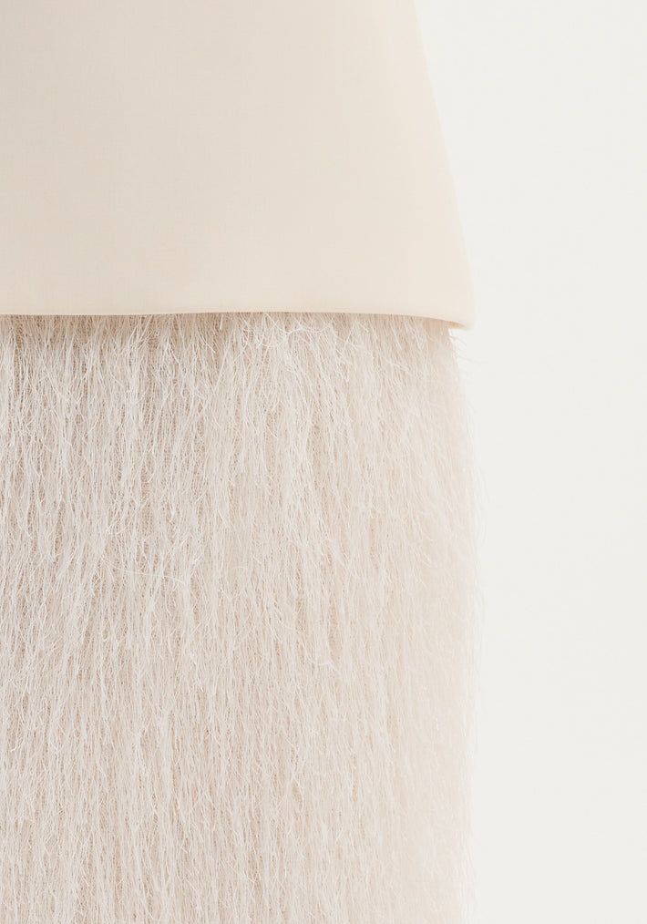 Close-up of an ivory Fringe skirt, showing detailed wool texture and fringe movement, with an invisible zip closure.