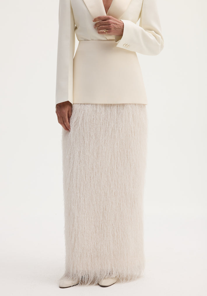 Person in ivory ensemble featuring Fringe skirt | ivory with tailored blazer; floor-length fringe adds movement. Cream shoes visible, hand adorned with a gold ring.