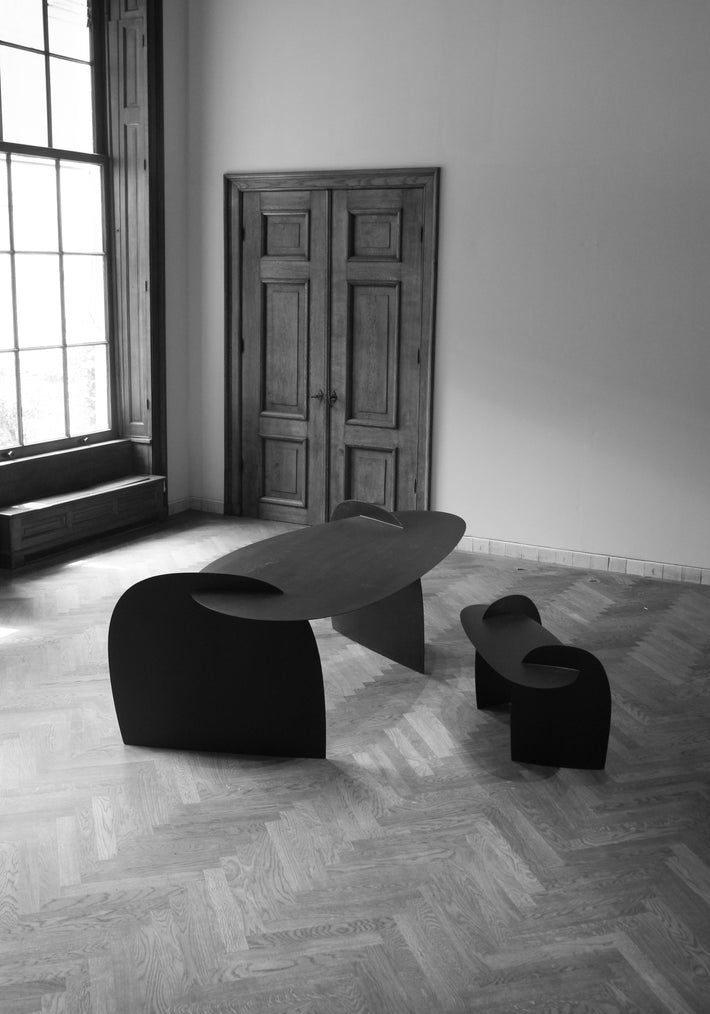 Sculpted Table | 9845: Abstract oak wood table by Arne Kristian, featuring curved, interlocking black panels in a minimalist, well-lit room with herringbone floor.