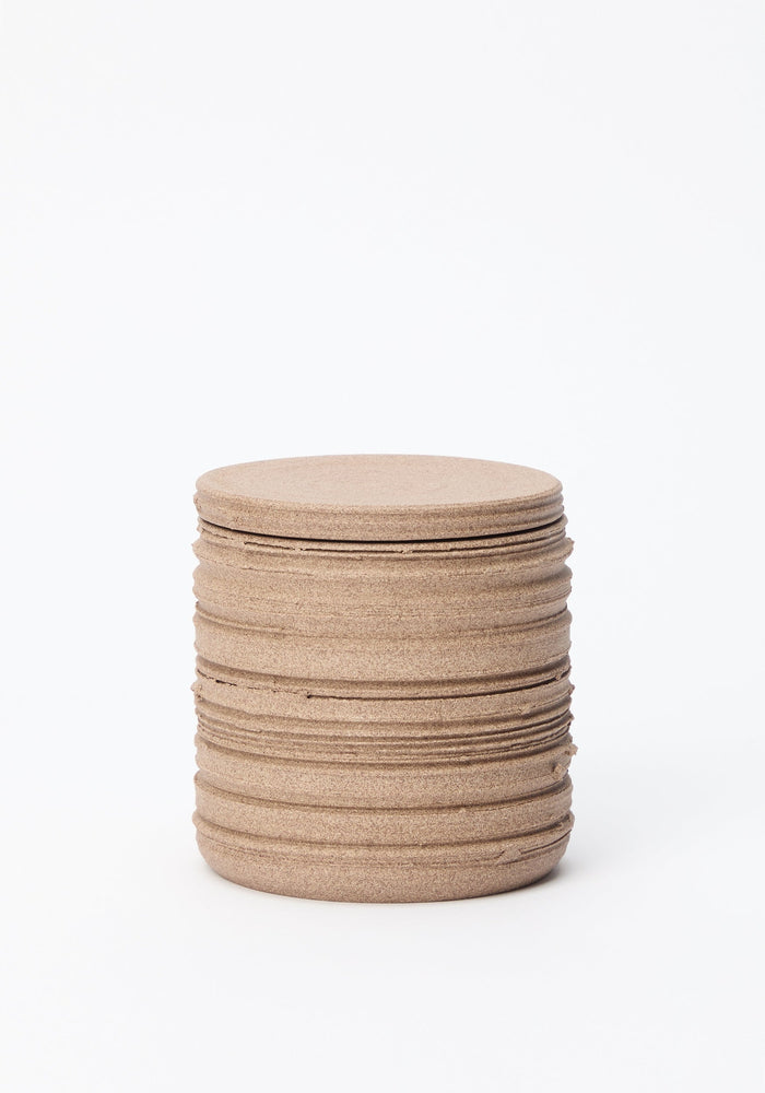 Diplomatico Scented Candle in a sand-colored, striated ceramic vessel, showcasing a brutalist design with a rough texture and circular top.