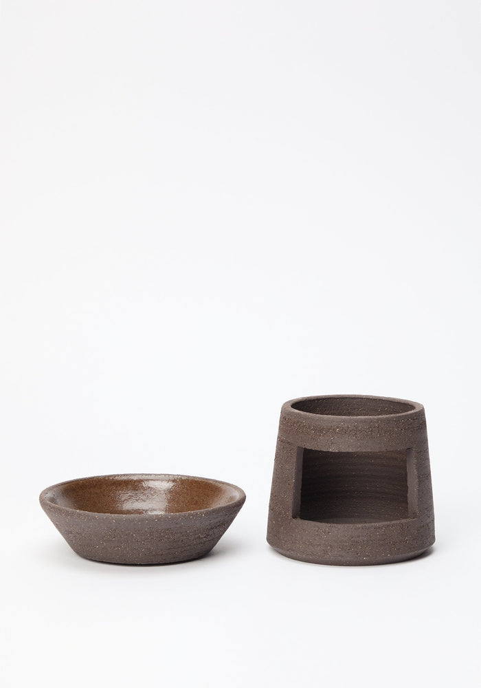 Ceramic Oil Burner | soil: Two handmade brown ceramic pieces—a shallow bowl and a cylindrical base with an opening—create a minimalist oil burner for diffusing scents.