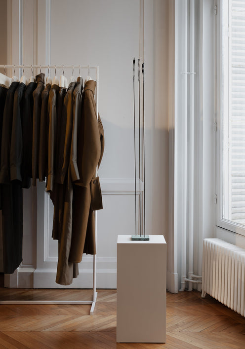 Bronze Sculpture | Dialogue: A minimalist abstract sculpture with four thin metal rods on a pedestal, created by Veri Wisman, showcased in a serene boutique interior.