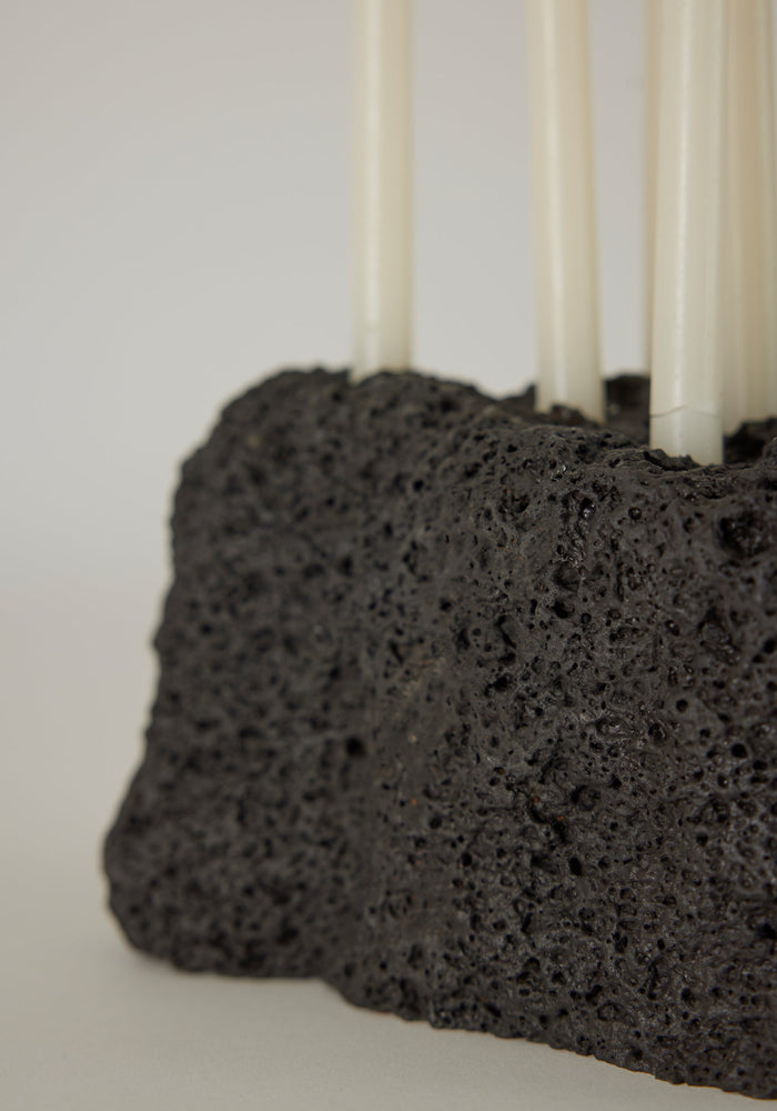 Sculptural Stone Candle Holder made from porous black lava stone, holds six white taper candles vertically, handcrafted by Dutch artist Louis Crombag.