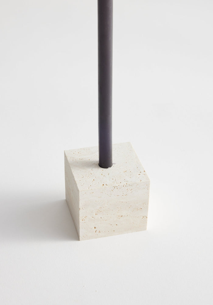 Two-way cube candleholder in travertine, featuring a square stone base with a slender taper candle, handcrafted by Louis Crombag in the Netherlands.