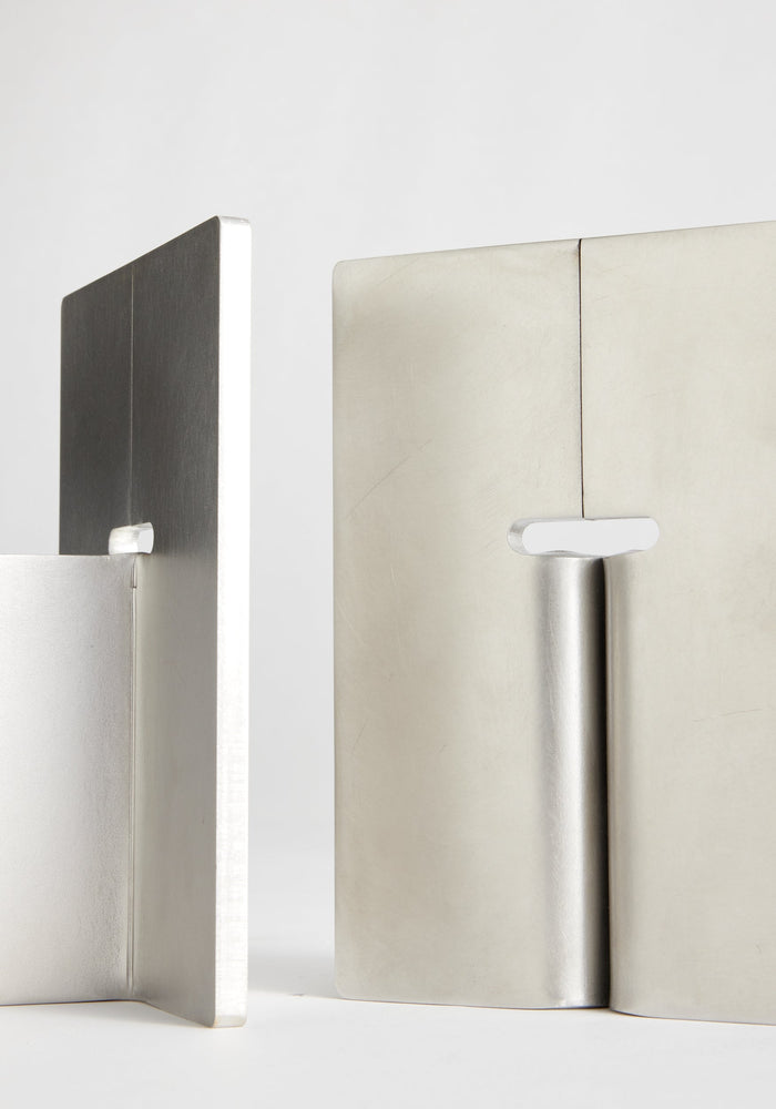Stainless steel bookends: Two minimalist, handcrafted bookends made of 8mm thick stainless steel, featuring a vertical plate with a base flange and an elongated slot.