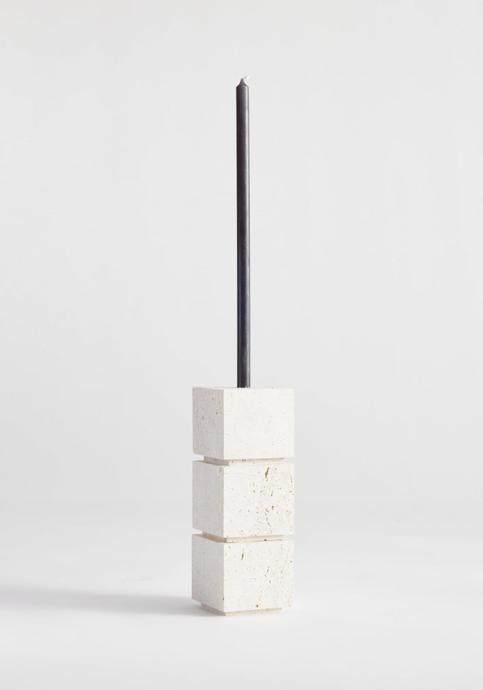 Sculptural candle holder small | travertine: Three stacked stone cubes with a black taper candle, handcrafted from Italian travertine by Dutch artist Louis Crombag.