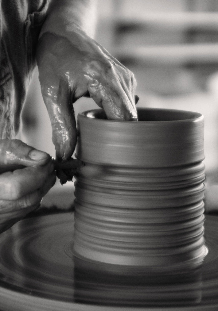 Potter shaping a clay vessel for the Diplomatico Scented Candle, showcasing crafted ridges on the ceramic, handmade by Alex Gabriels, reflecting a brutalist design.