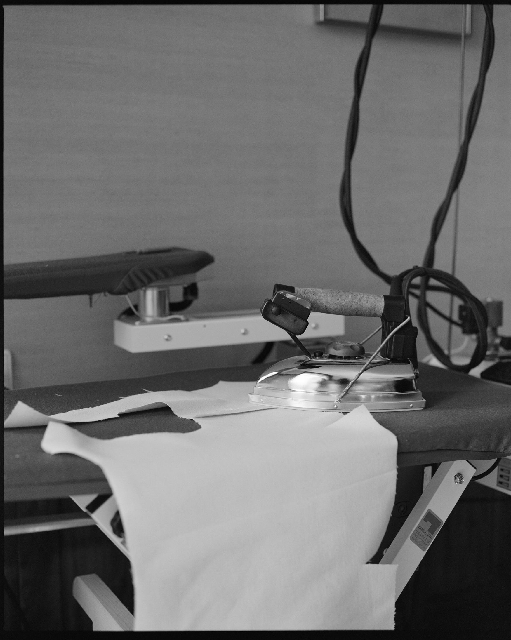 Ironing board with iron and clothes against a linnen covered wall