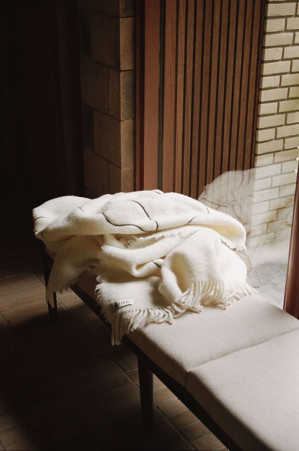 White blanket draped over a bench in a dimly lit room with brick walls.