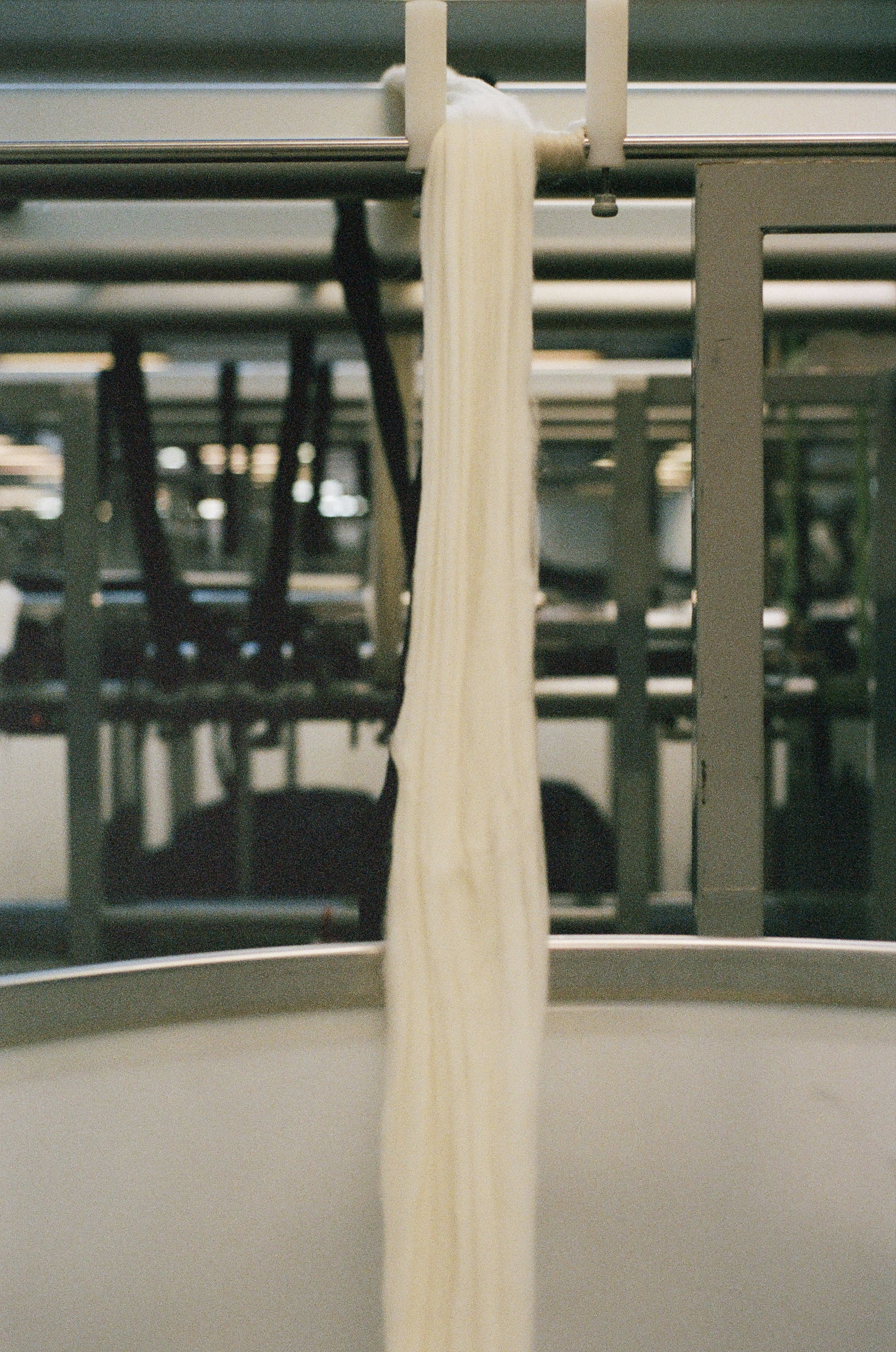 White wool yarn hanging from a metal rod in an industrial setting