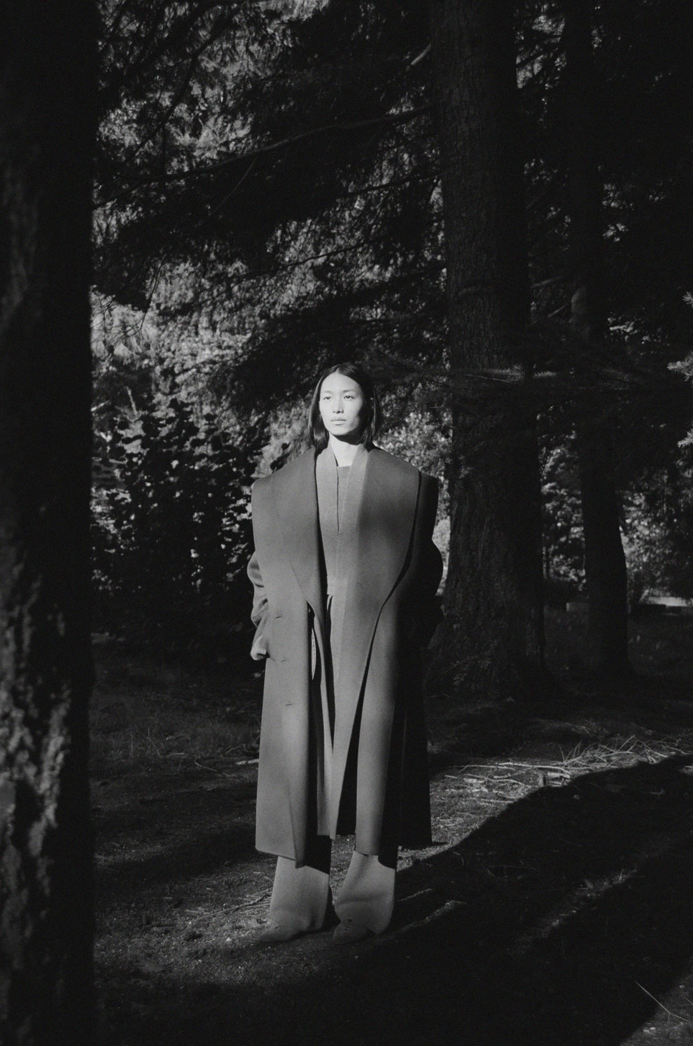 Woman standing in a forest with a long coat