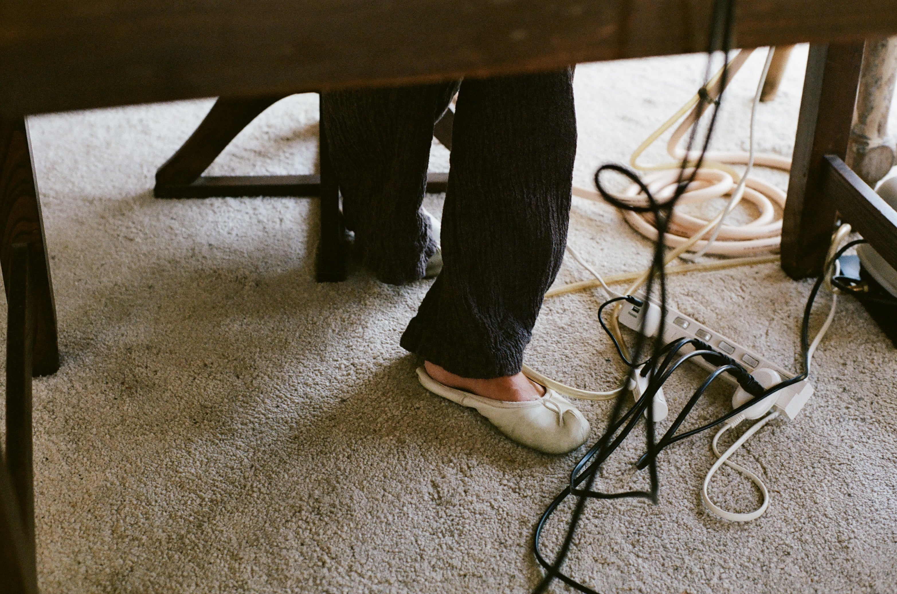 Feet underneath a table with cords 