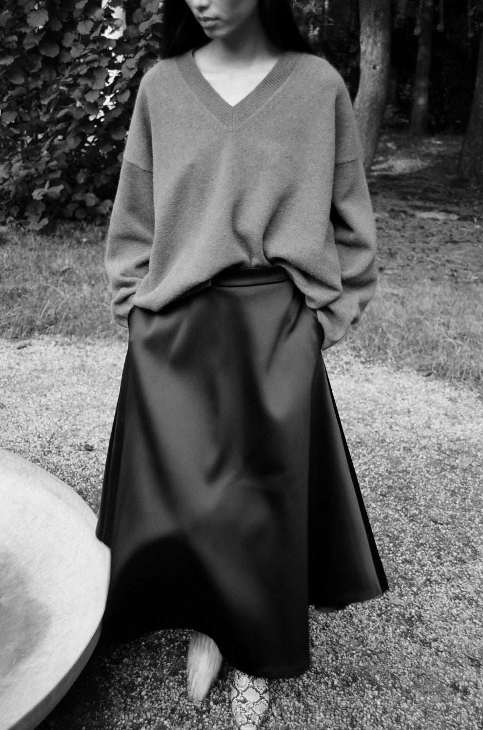 Woman wearing a v-neck sweater and heavy satin a-line skirt.
