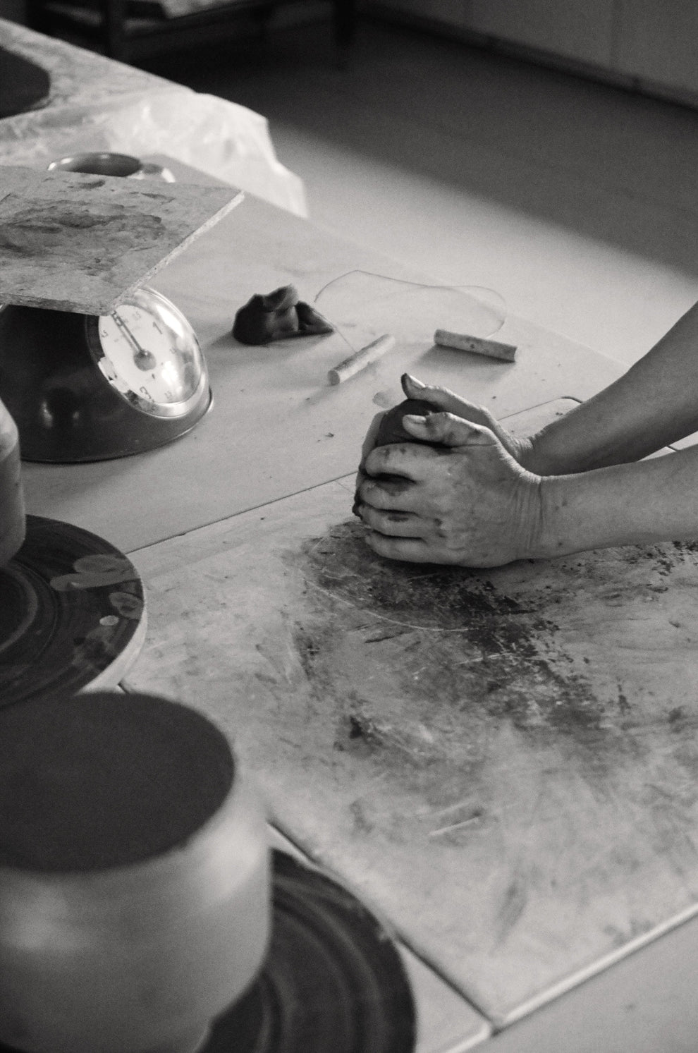 Person working with clay on a work table in a studio setting