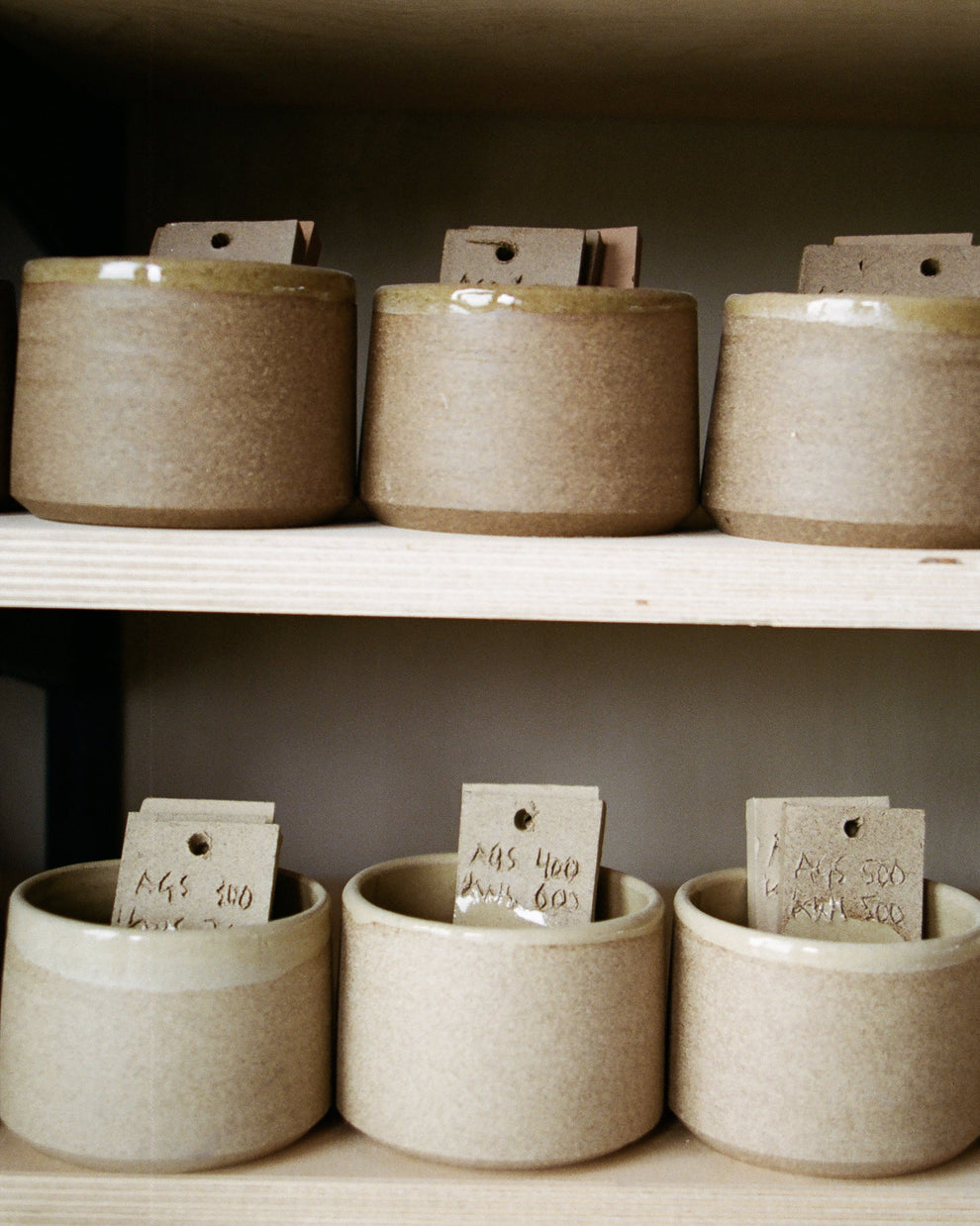 Set of ceramic pots in differen colors on a shelf with color labels