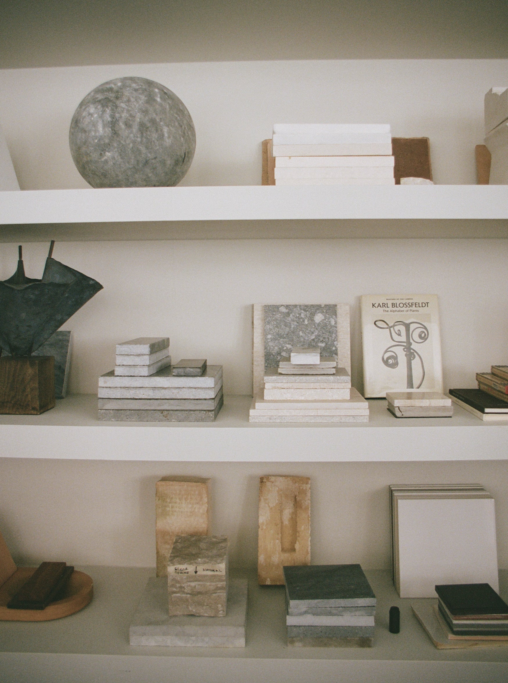 Shelves with books, decorative items, and a spherical object on a neutral background