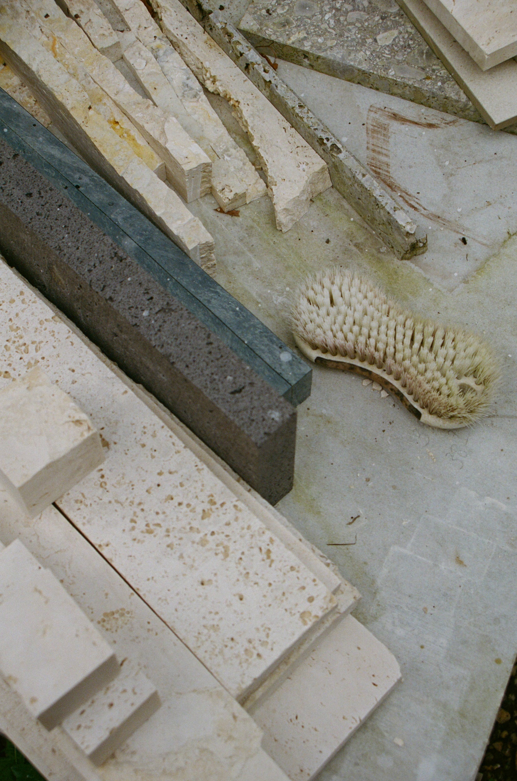 Pieces of travertin and a brush on a concrete floor