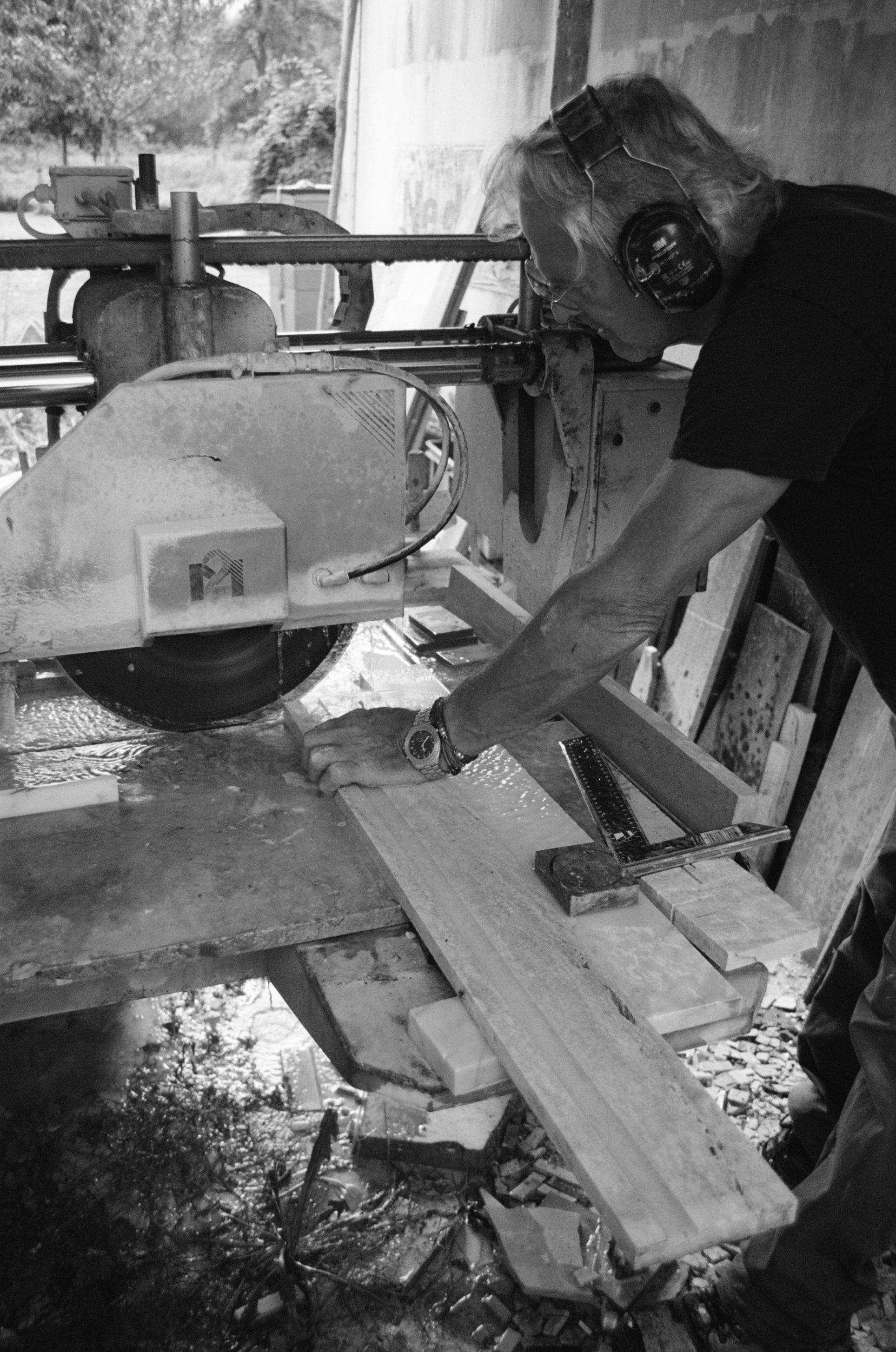 Man using an electric circle saw to cut travertine stone into smaller pieces