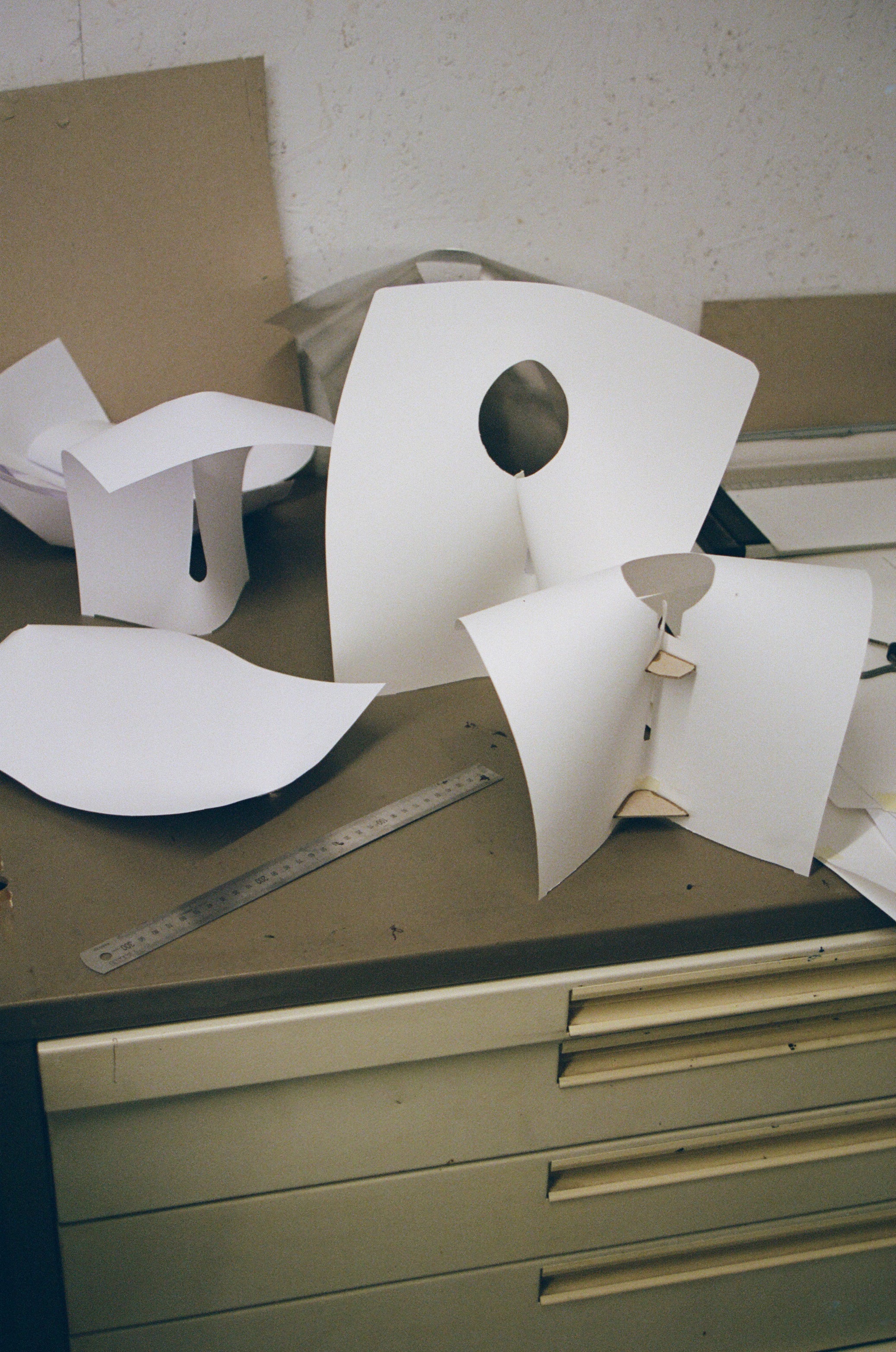 White paper cutouts on a wooden surface with a ruler