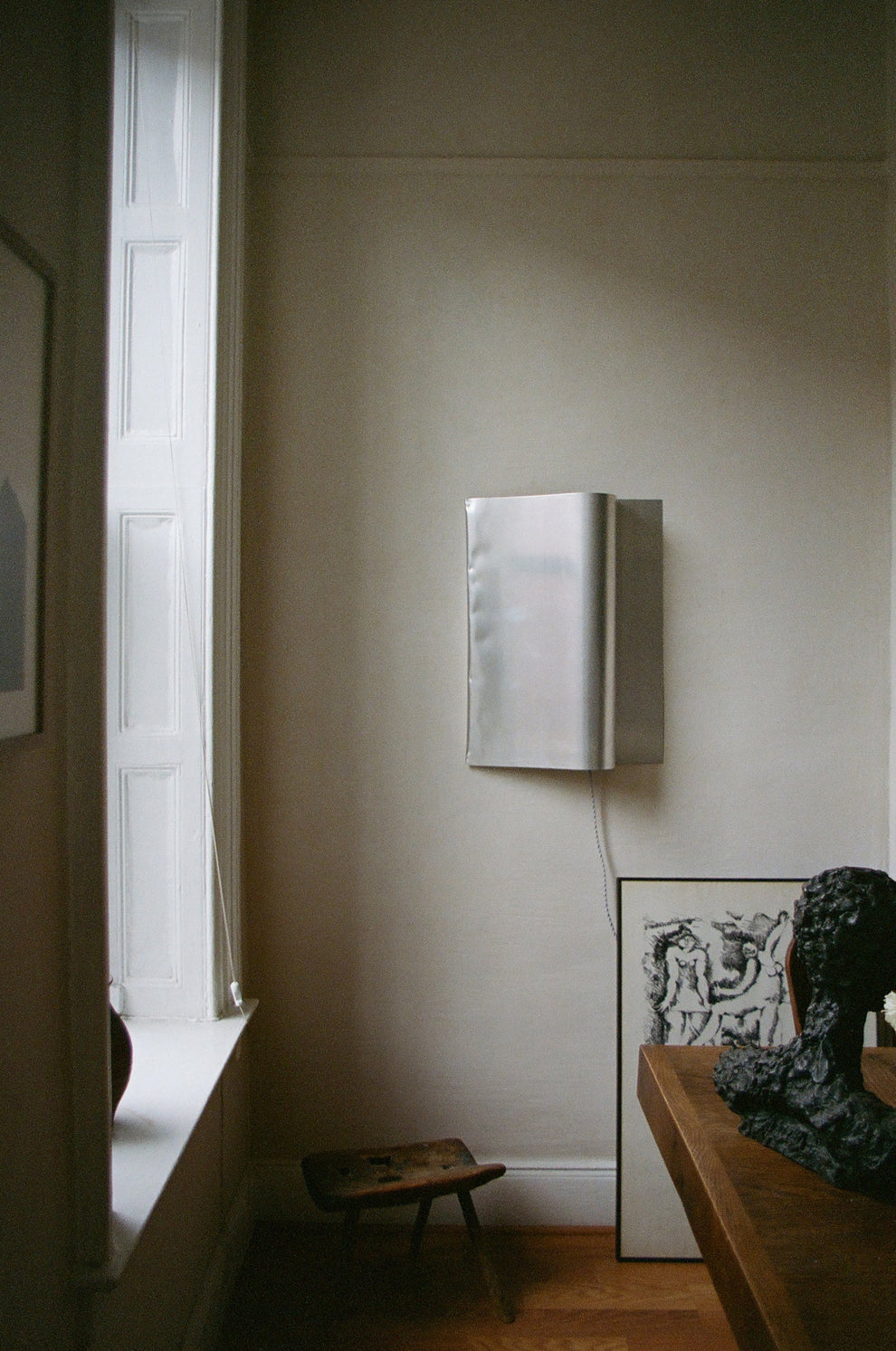 Stainless steel wall lamp hanging next to a window 