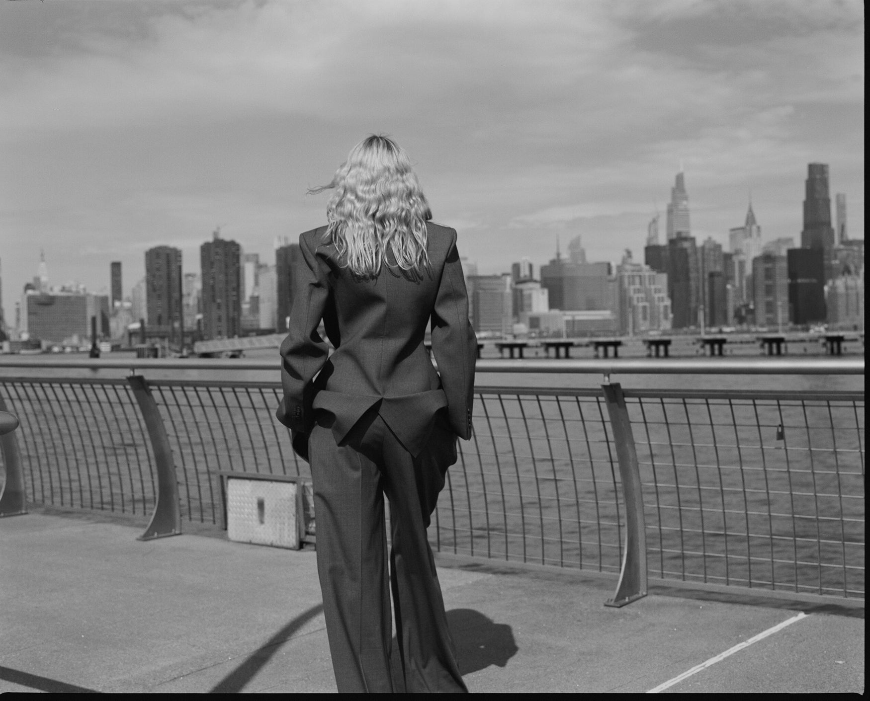 Woman photographed from the back  wearing a grey suit overlooking the New York city skyline