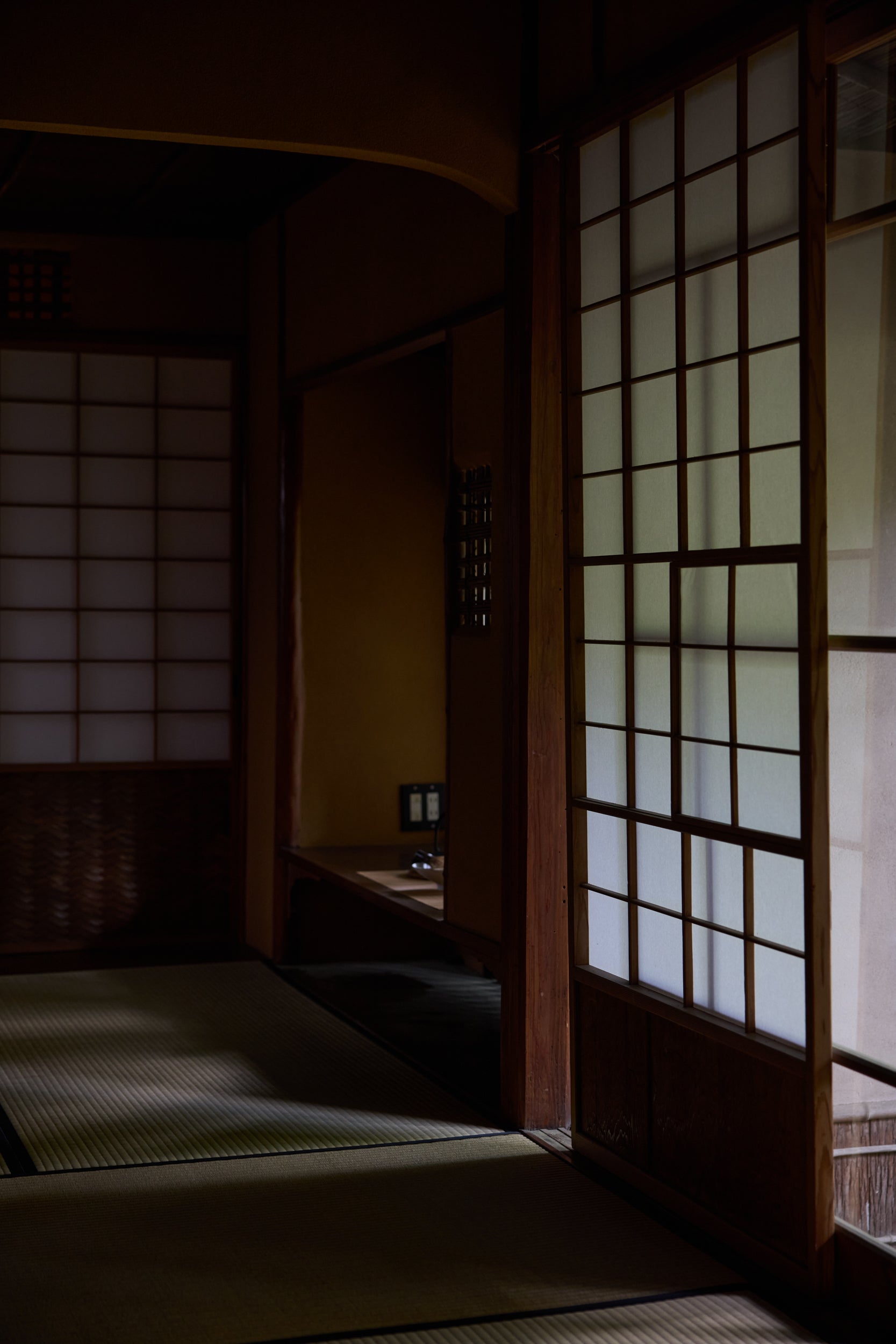 Interior of a Japanese tea house with light filtering through the shoji doors. 