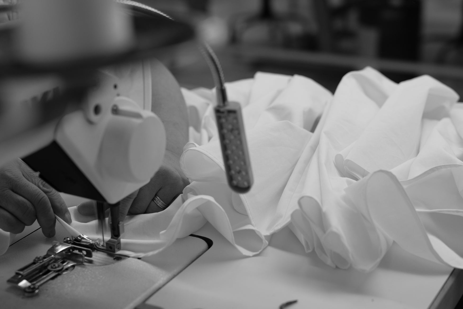 Sewing machine with white cotton fabric in a workshop setting