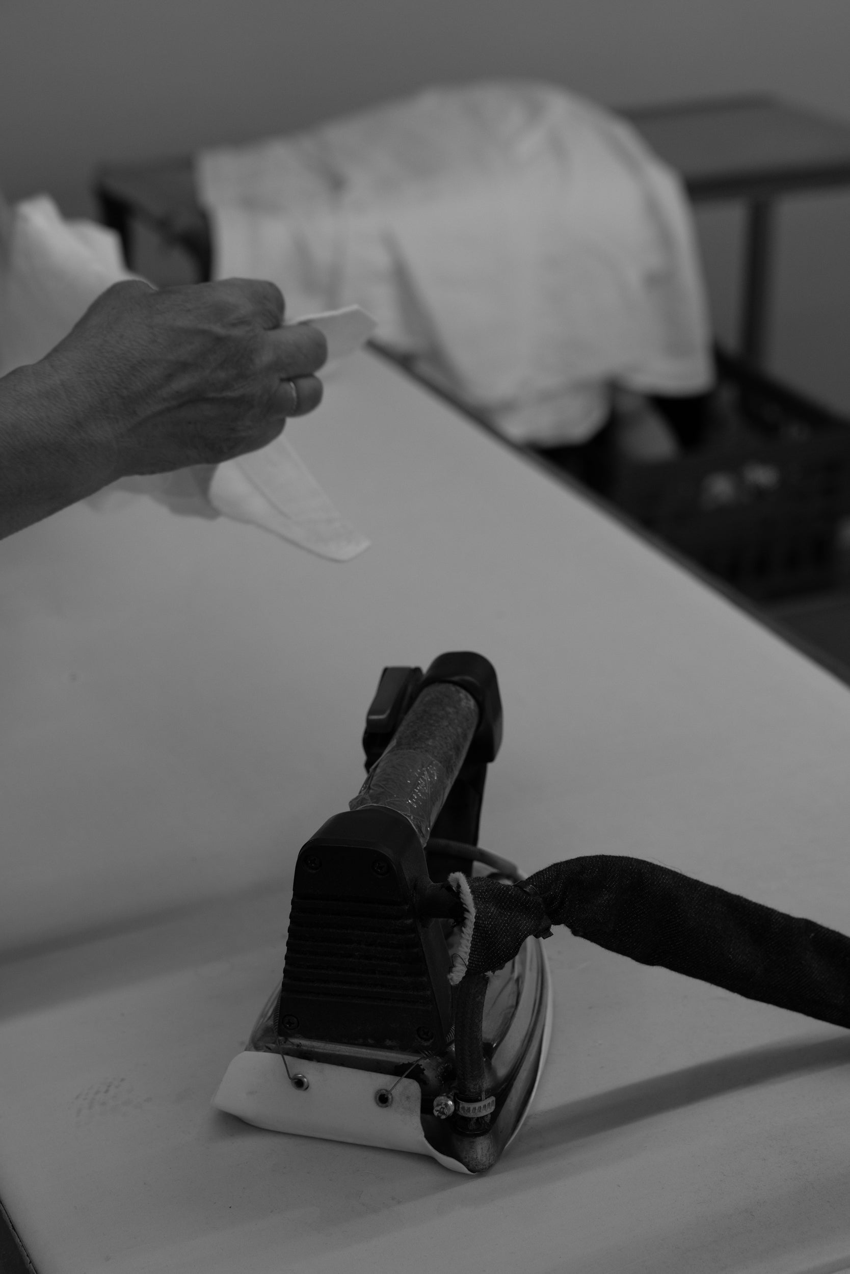 Person ironing a garment on a table with a blurred background