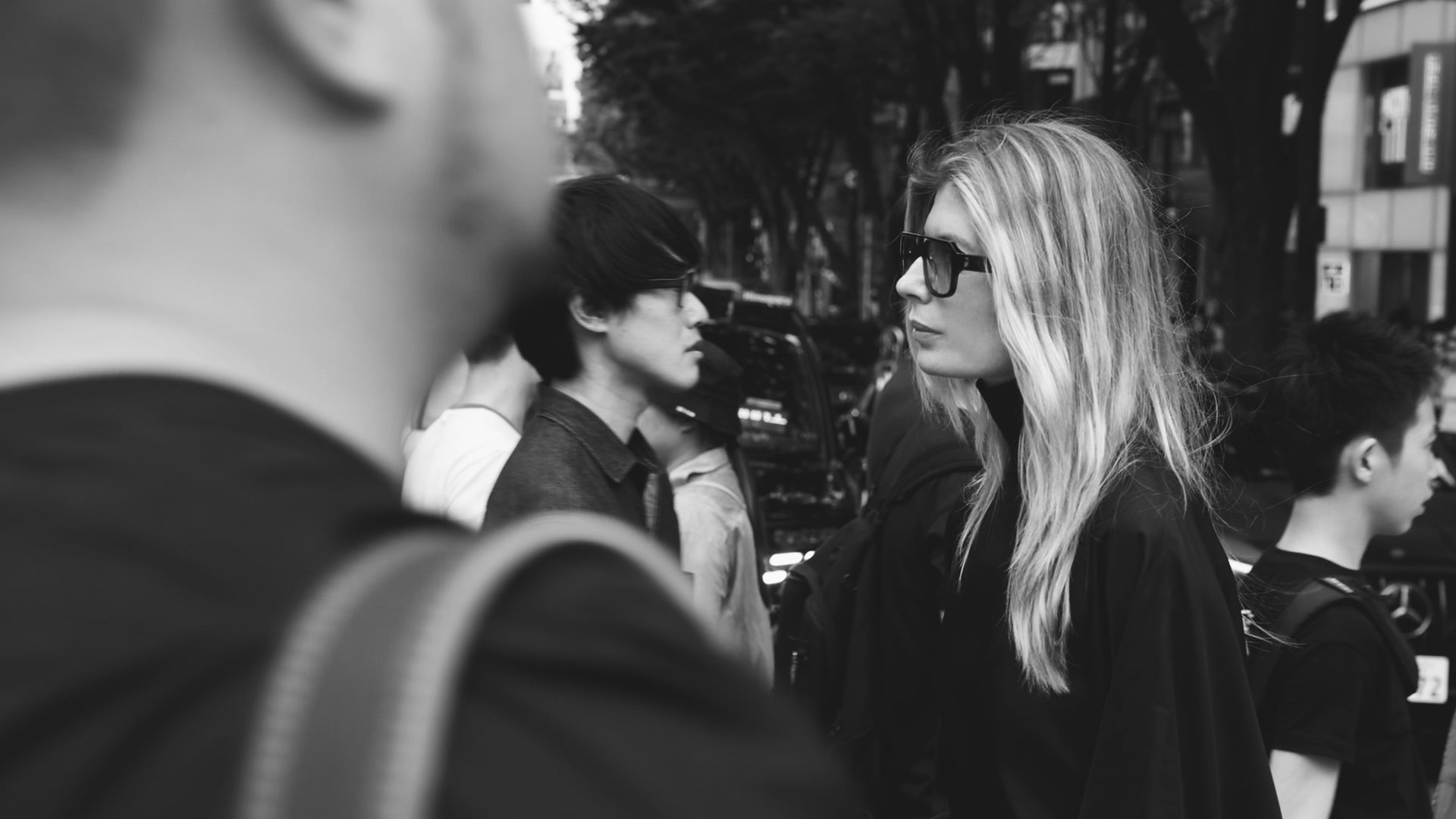 Blonde woman in the streets wearing big sunglasses surrounded by people 