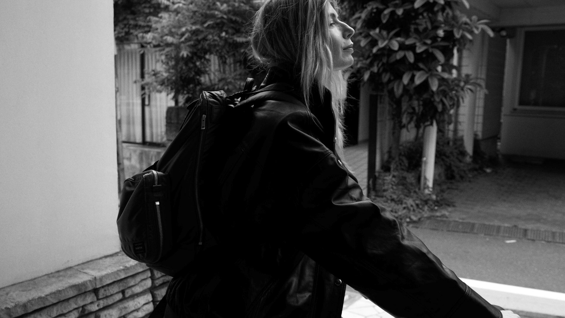 Woman from the side hoding a bike and wearing a backpack in a street in Tokyo