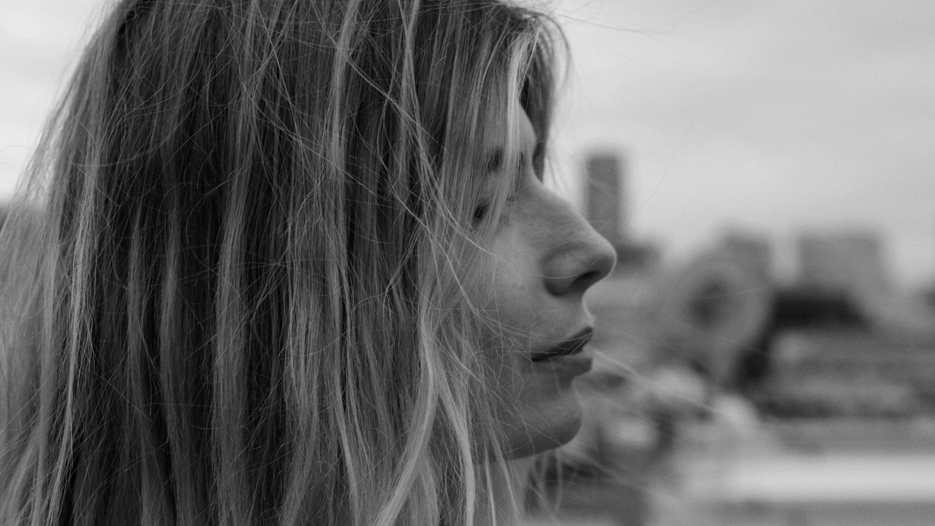 Close-up of the profile of the face of a blonde woman standing on a rooftop